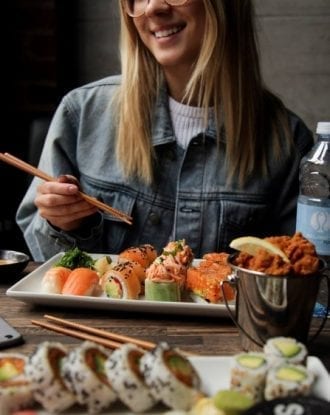 Girl eating a platter of various sushis