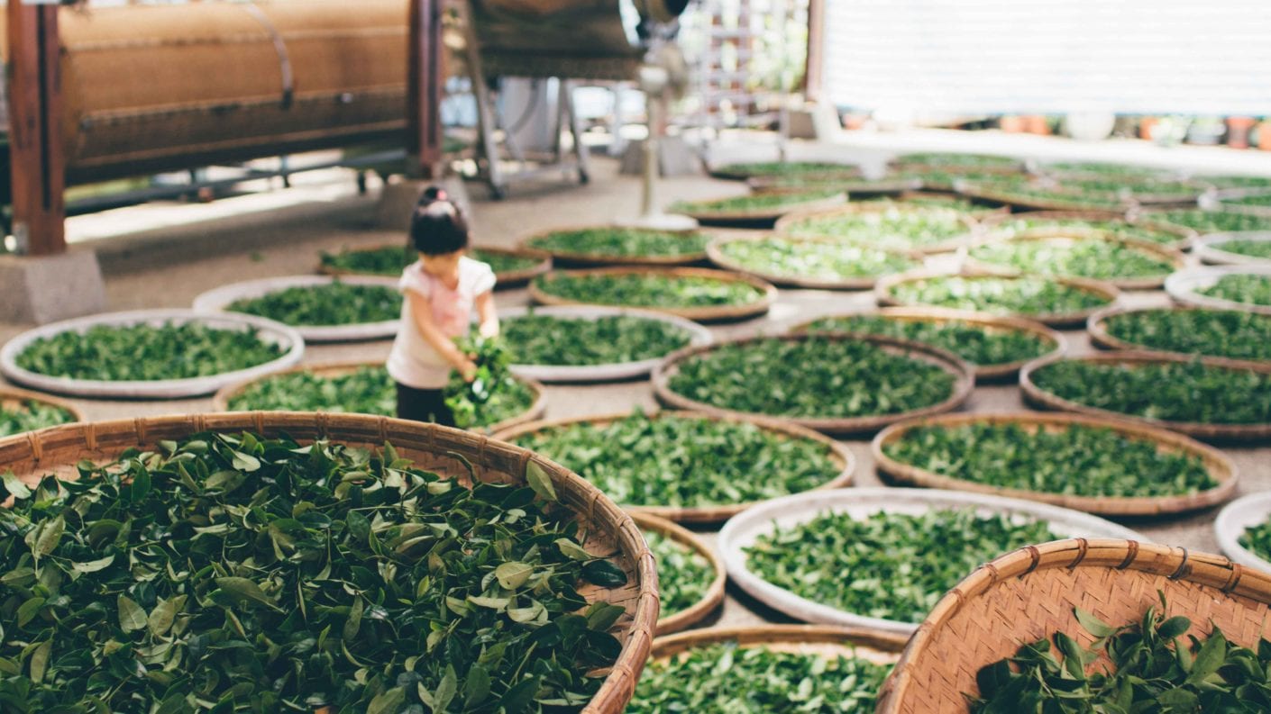 A young Japanese girl is surrounded by baskets of tea